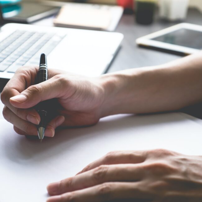 Close up of male hands writing on paper on his office desk.