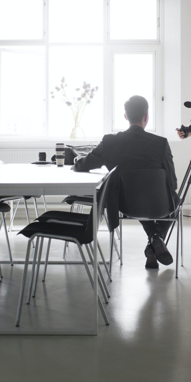 Photographer recording interview of businessman in board room